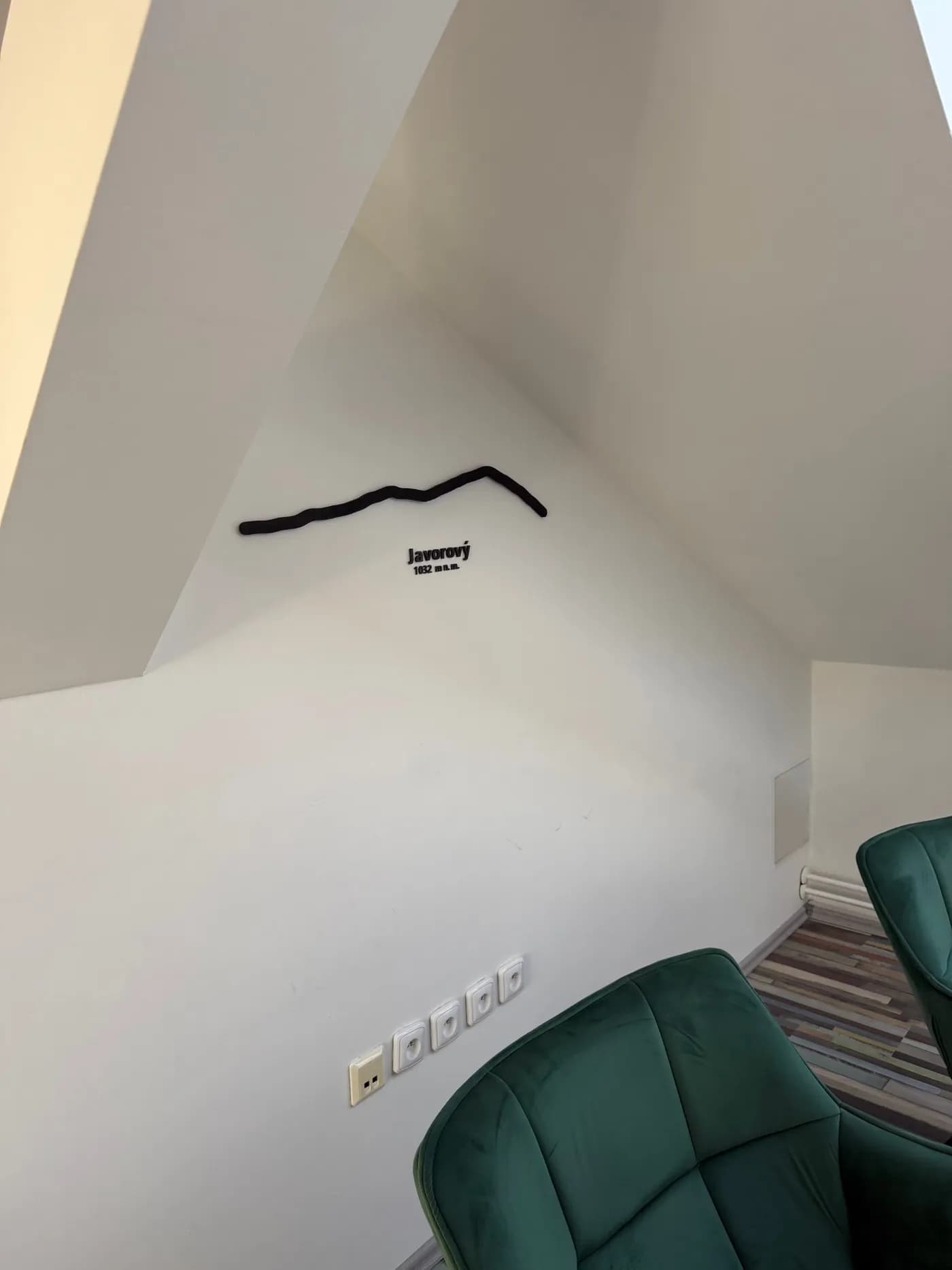 3D tištěná silueta Javorového s nápisem Javorový 1032 m n. m. na zkosené stěně podkroví