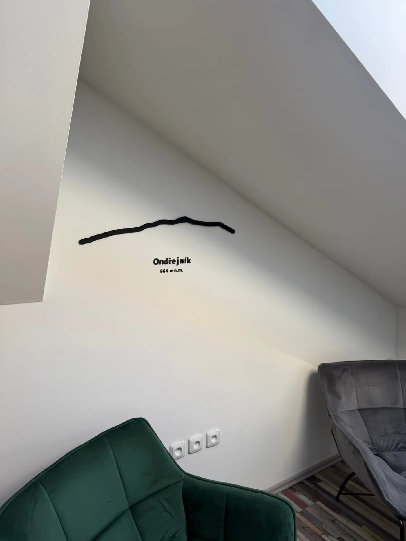 3D tištěná silueta Ondřejníku s nápisem Ondřejník 964 m n. m. nad křesly v kanceláři
