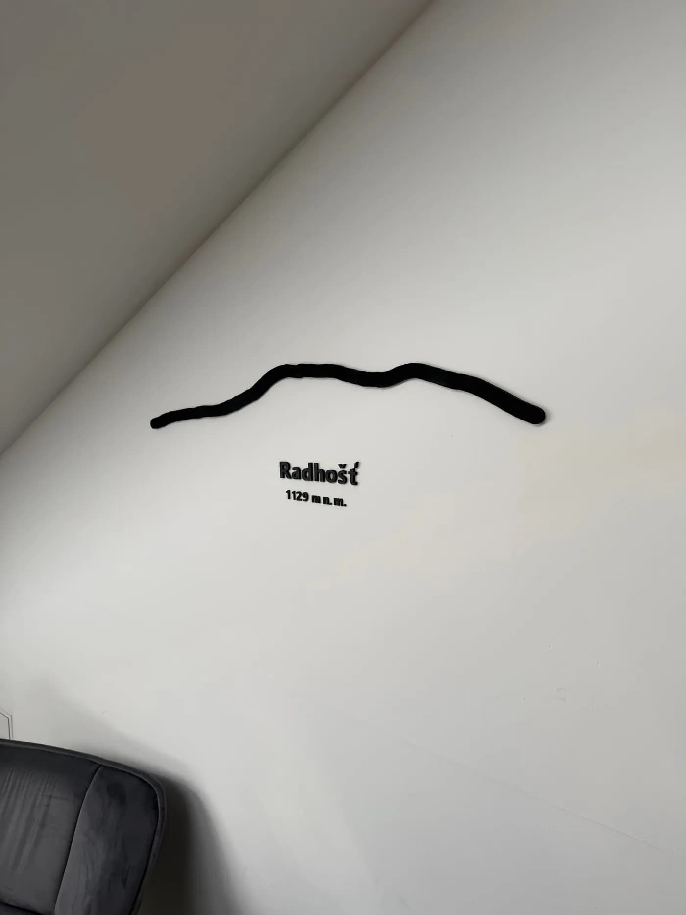 3D tištěná silueta Radhoště s prostorovým nápisem Radhošť 1129 m n. m. na bílé stěně
